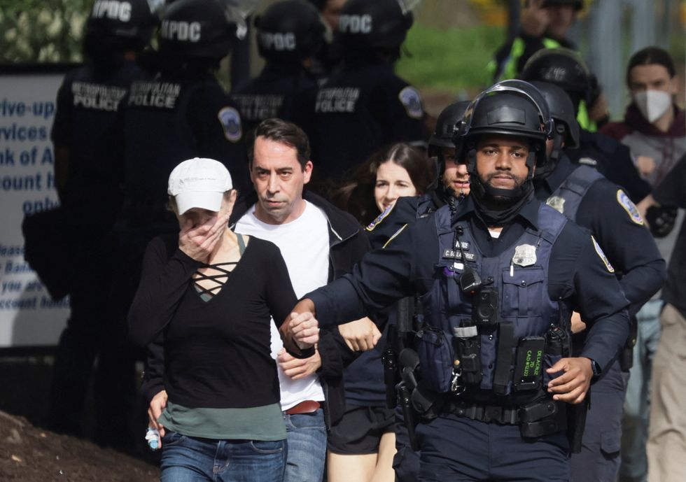 A woman reacts as she runs with Washington, D.C. Metropolitan Police officers and other local residents as police evacuate people to safety at the scene of a reported shooting and active shooter near Edmund Burke Middle School in the Cleveland Park neighborhood of Northwest Washington, U.S., April 22, 2022. REUTERS/Evelyn Hockstein