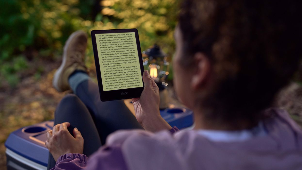 a woman reads on her Kindle with the backlight on outdoors on a camping trip