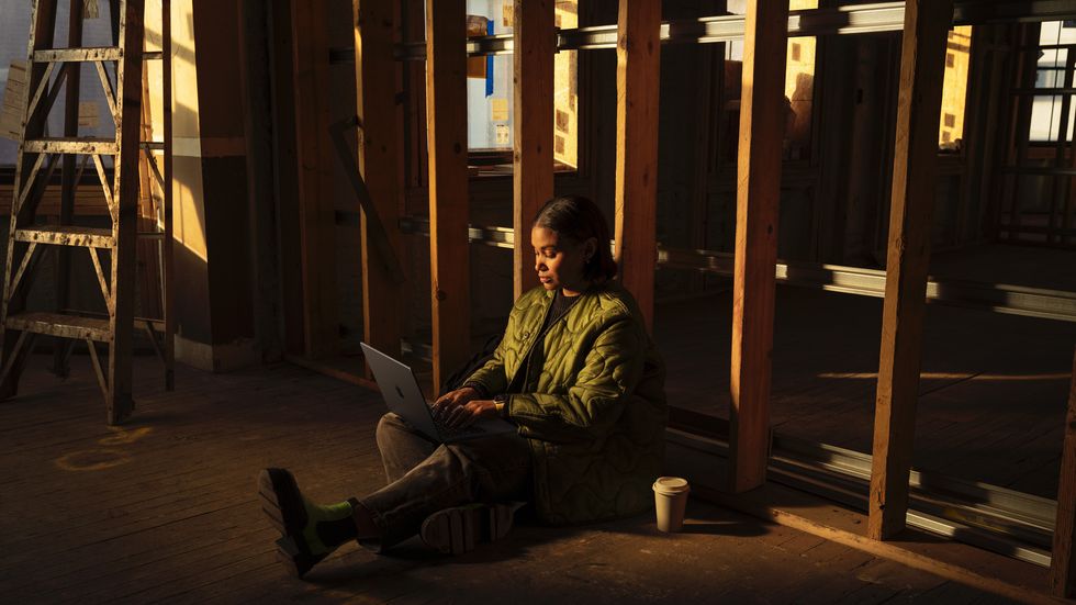 a woman sits on the floor with a coffee using the new space black macbook pro