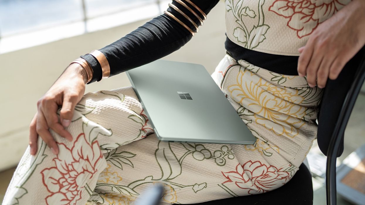 a woman sits with a surface laptop resting on her lap