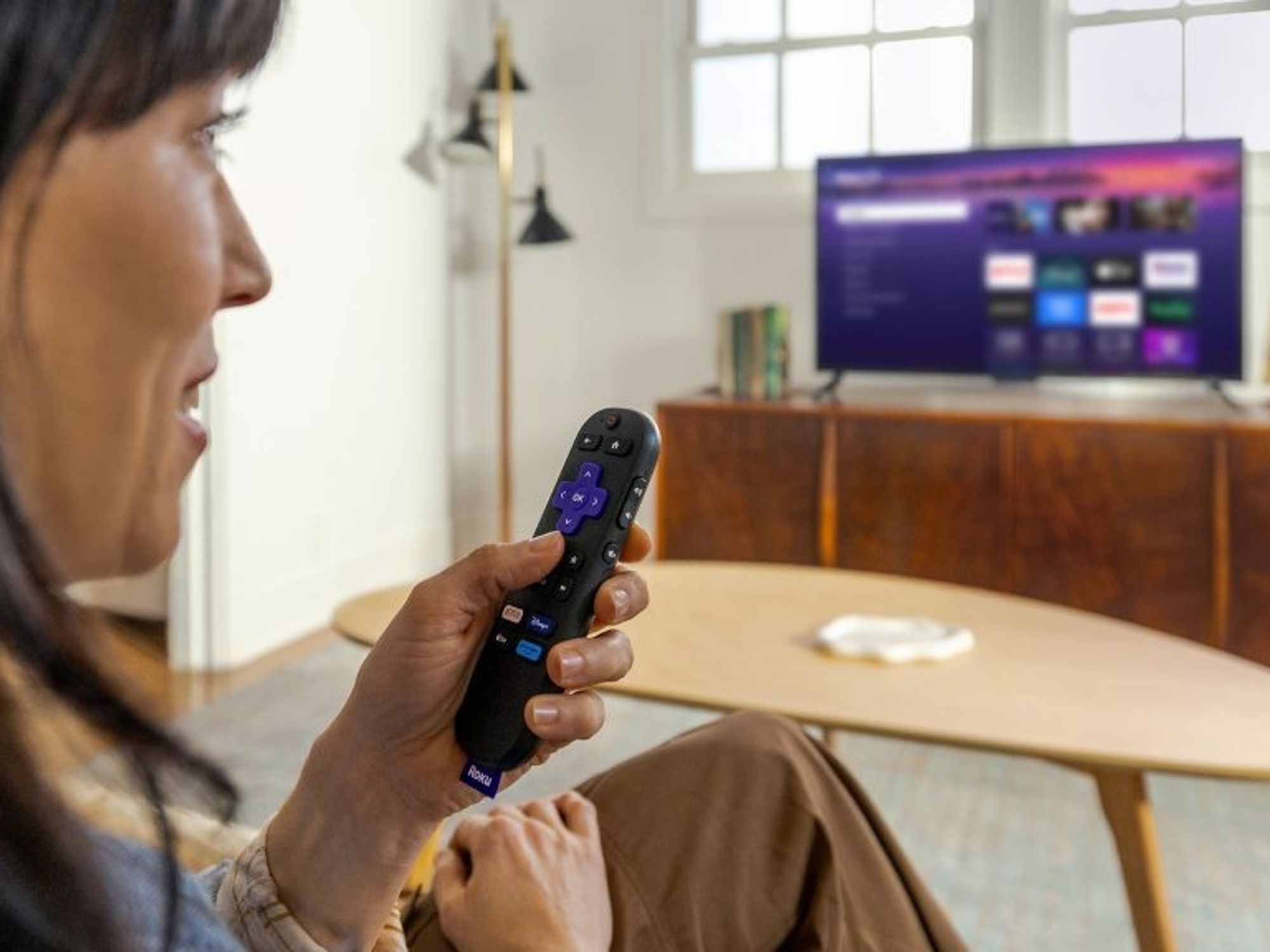 a woman speaks into the voice control remote of the new Roku Streaming Stick