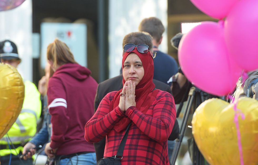 A woman stands by floral tributes in St Ann's Square, Manchester, ahead of a minute's silence to remember the victims of the terror attack in the city earlier this week.