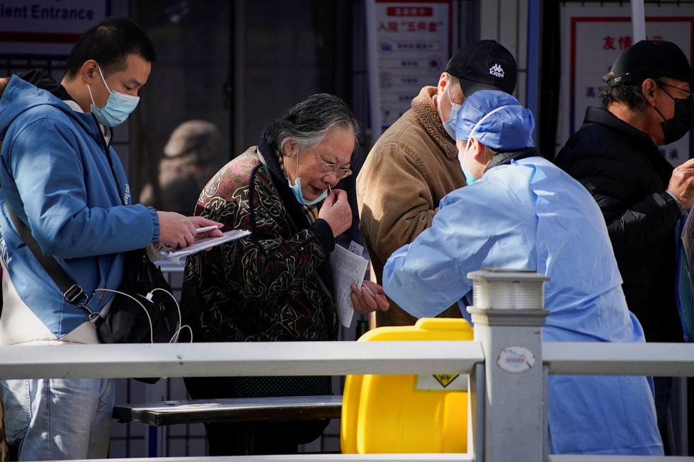 A woman takes a rapid antigen test for COVID-19 at an entrance of a hospital, as coronavirus disease (COVID-19) outbreaks continue in Shanghai, China, December 13, 2022. REUTERS/Aly Song