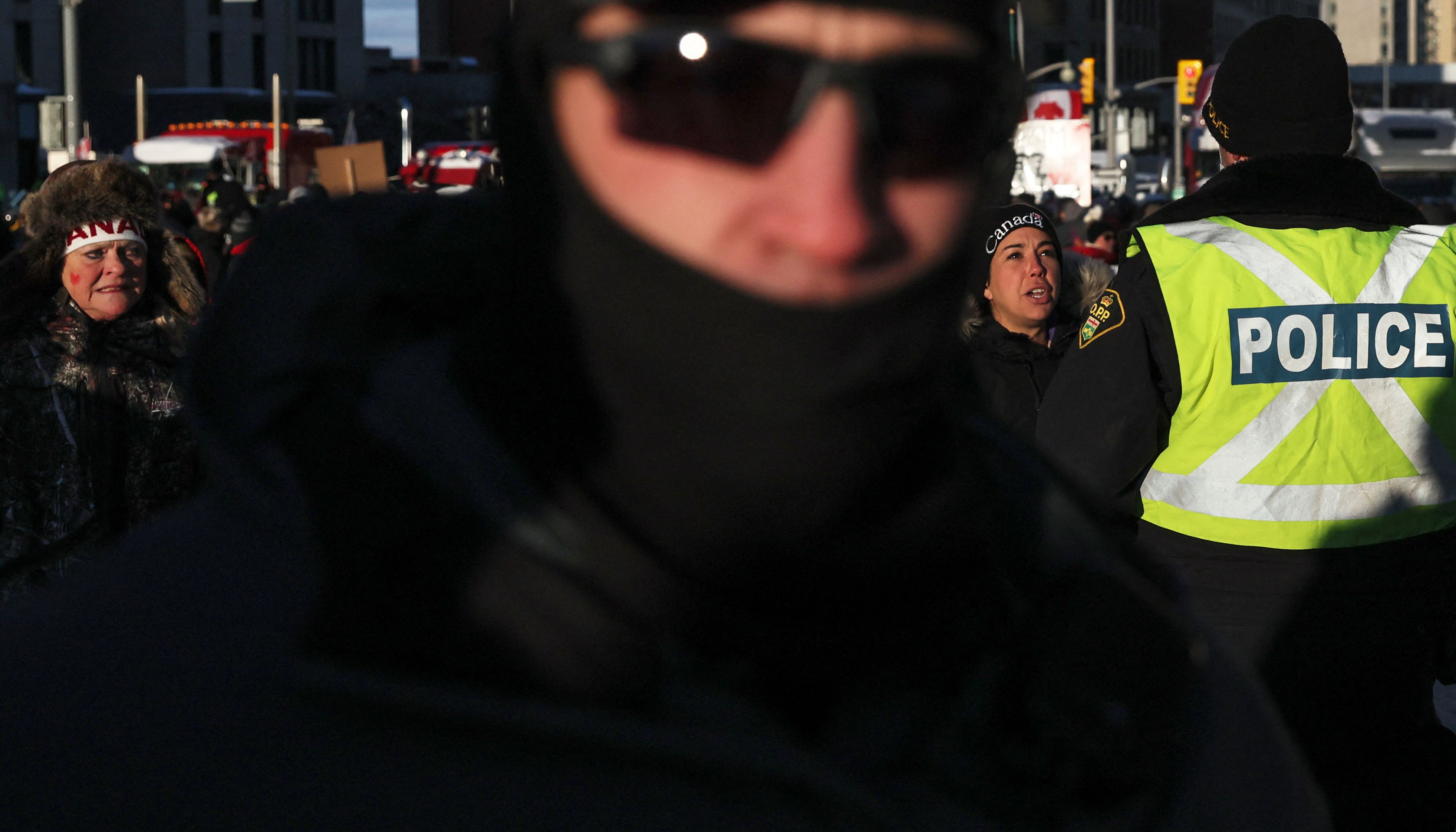 A woman talks with Police officers as they stands guard, while truckers and supporters continue to protest Covid vaccine mandates, on Wellington Street in Ottawa, Canada
