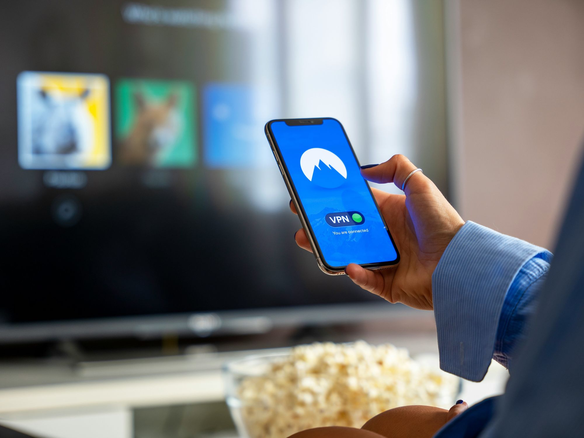 a woman turns on a nordvpn connection on her phone with Netflix in the background
