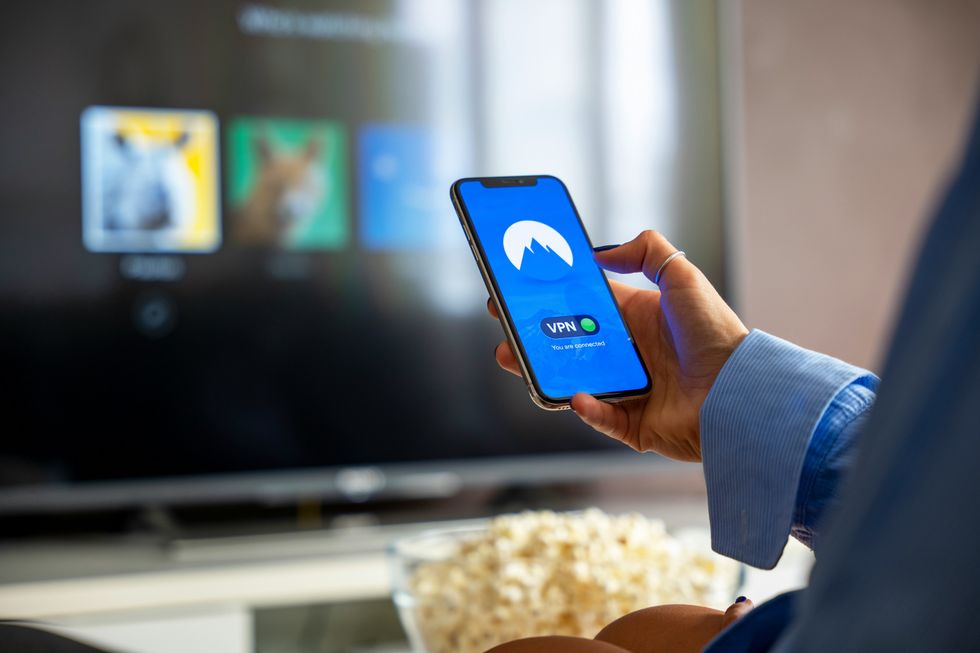 a woman turns on a nordvpn connection on her phone with Netflix in the background