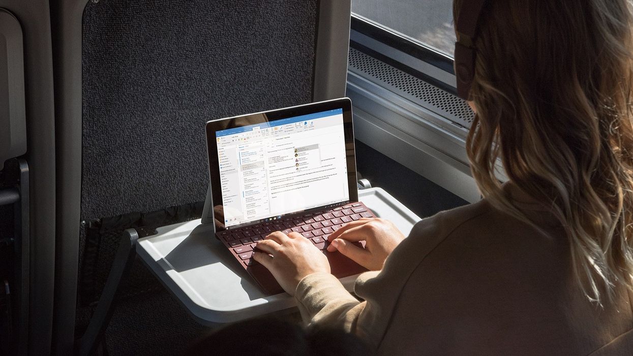 a woman typing on a keyboard on a surface tablet on the train