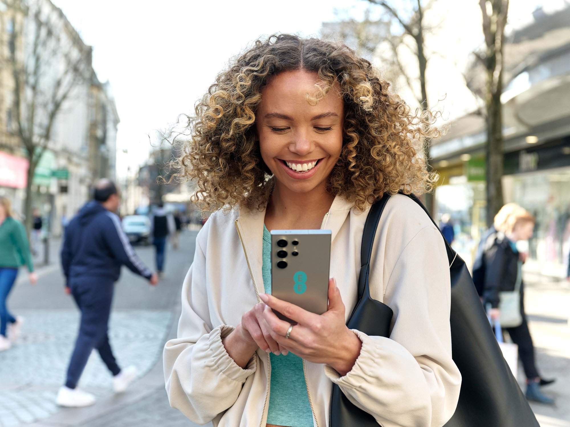a woman uses a samsung galaxy handset with an ee sticker on the back
