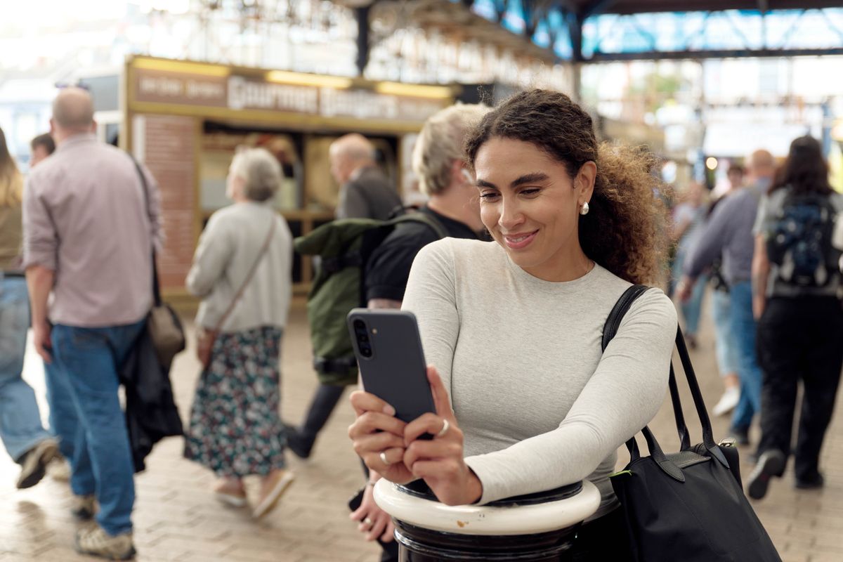 a woman uses her smartphone in a busy christmas market