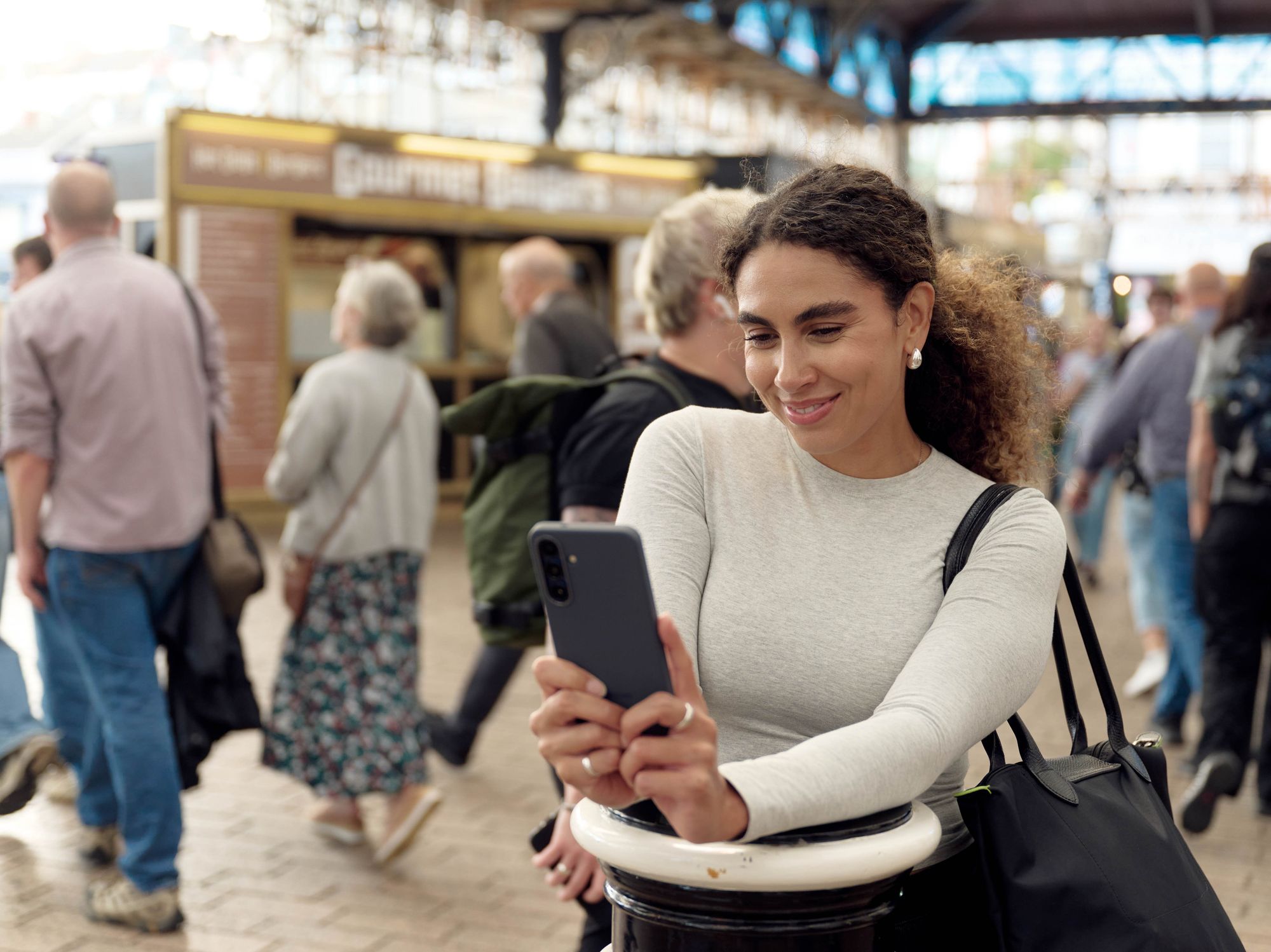 a woman uses her smartphone in a busy christmas market