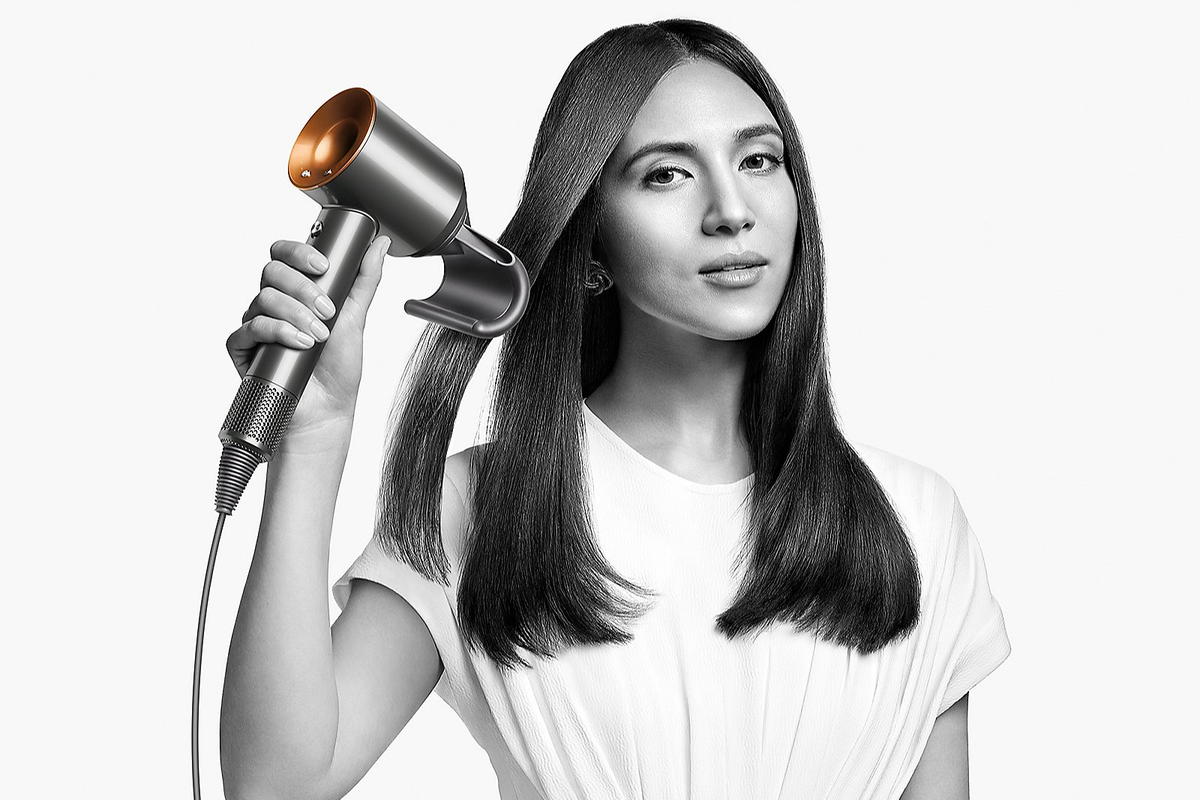 a woman uses the Nickel/Copper dyson supersonic hairdryer to dry her hair