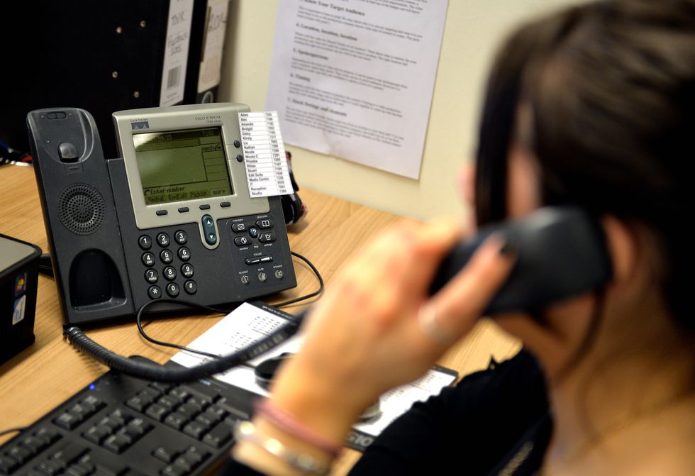 A woman using a landline phone in an office