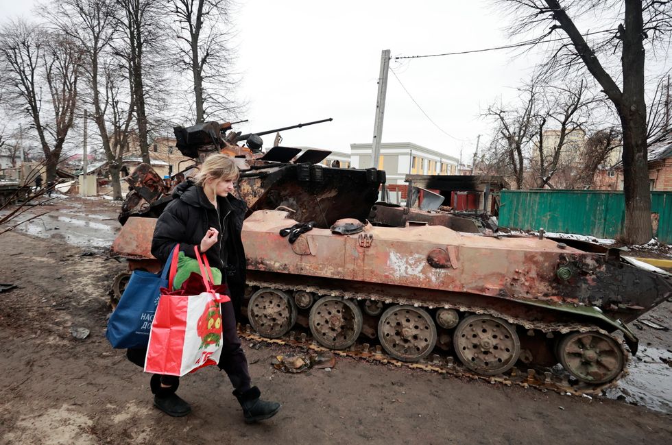 A woman walks past a destroyed military vehicle, as Russia's invasion of Ukraine continues, in the town of Bucha in the Kyiv region, Ukraine March 1, 2022. Picture taken March 1, 2022. REUTERS/Serhii Nuzhnenko