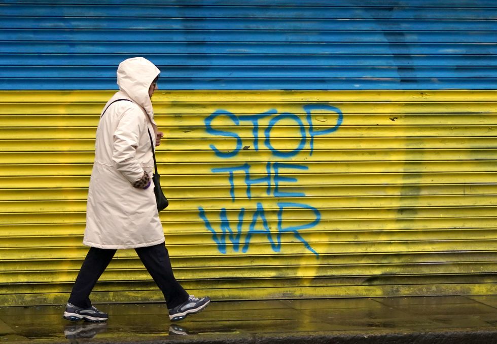 A woman walks past anti-war graffiti in support of Ukraine, painted on shutters in Dublin city