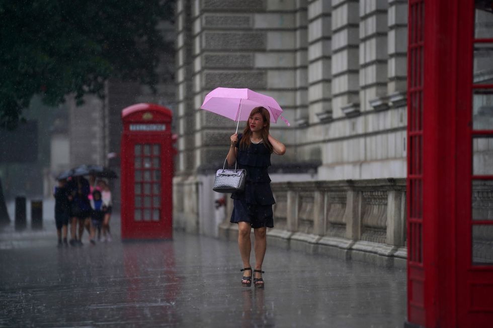 A woman walks through Parliament Square as heavy rain sweeps through central London.