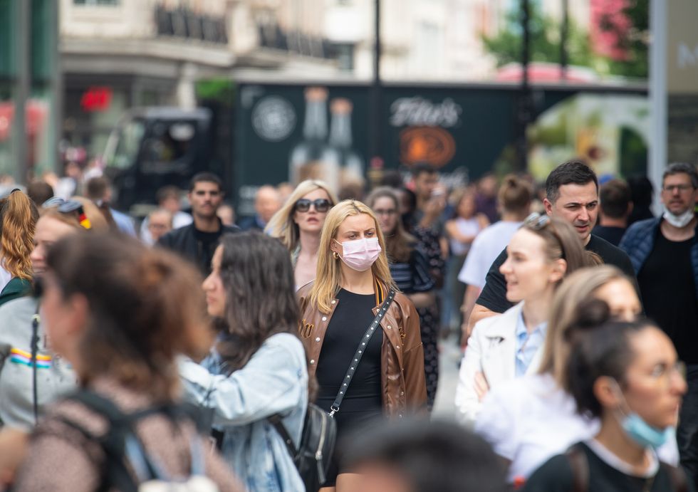 A woman wearing a face mask among a crowd of pedestrians on Oxford Street, London
