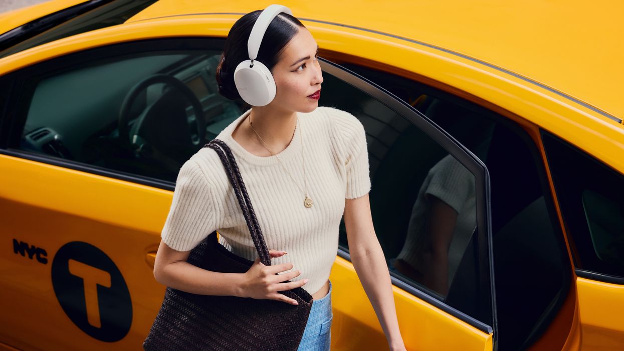 a woman wearing sonos ace headphones getting into a yellow new york cab