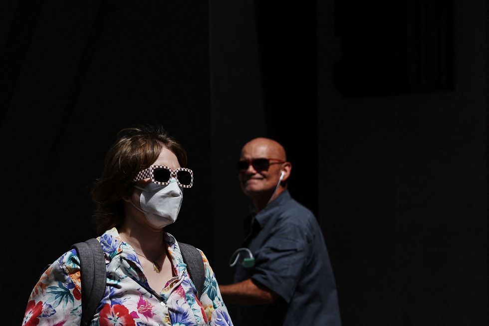 A woman wears a protective face mask walking down the sidewalk in the Midtown area of New York City