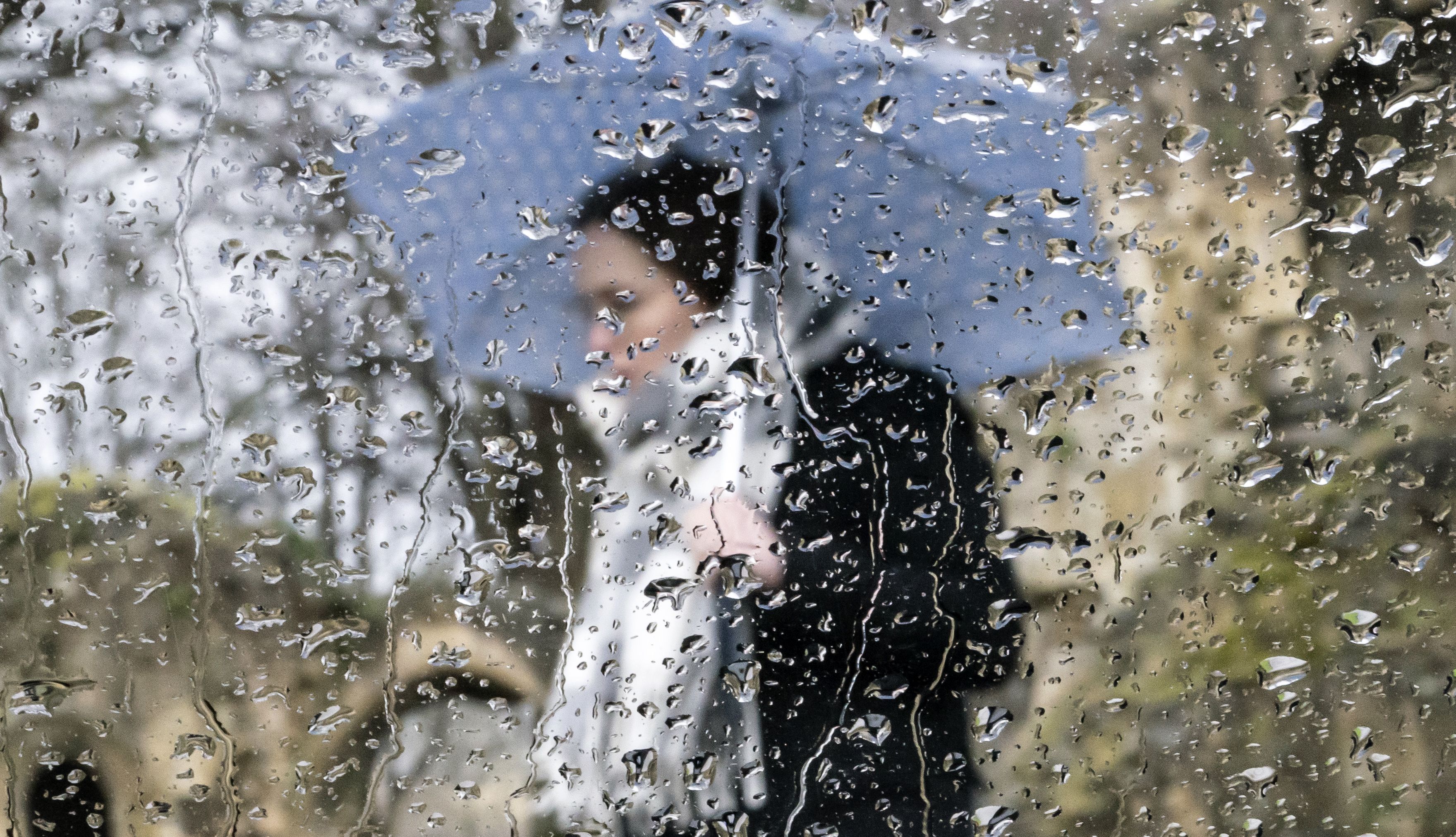 A woman with an umbrella is seen through a rain covered window near Knaresborough Castle in North Yorkshire. Picture date: Saturday February 5, 2022.