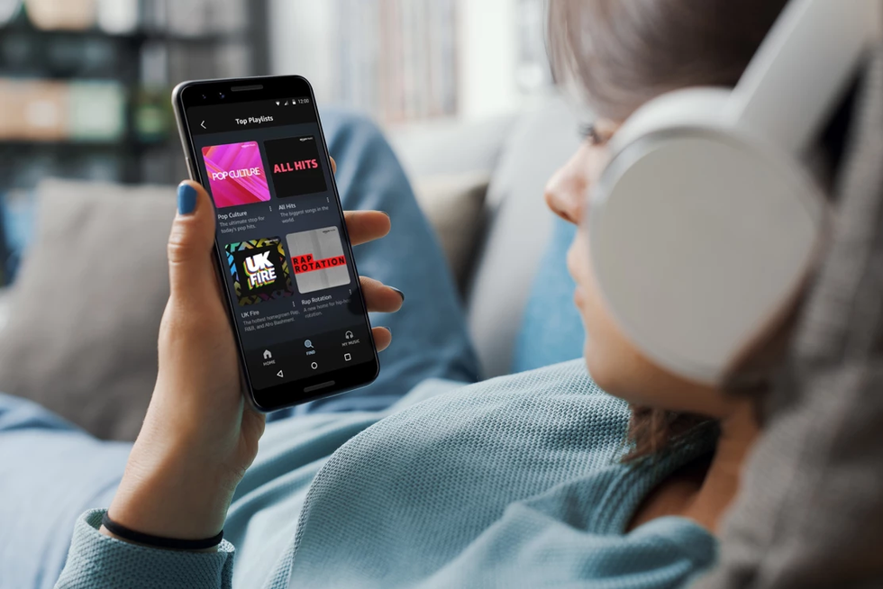 a woman with headphones listening to songs on the amazon music app on iphone