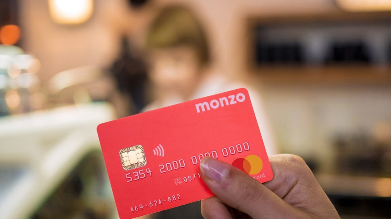 a womans hand holding a monzo bank card