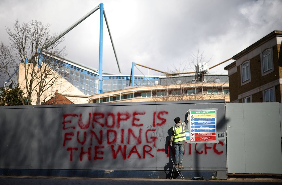 A worker begins to paint over graffiti on hoardings outside Chelsea Football Club's stadium, Stamford Bridge, following Britain's imposing of sanctions on the club's Russian owner, Roman Abramovich, in London, Britain, March 12, 2022. REUTERS/Henry Nicholls
