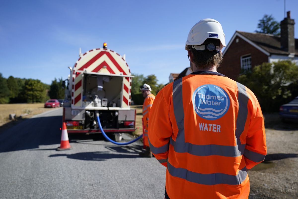A worker from Thames Water delivering a temporary water supply from a tanker