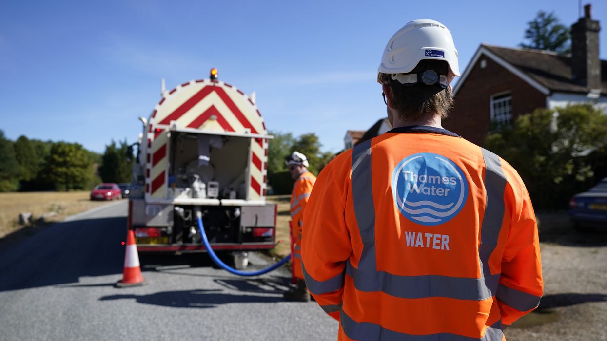 A worker from Thames Water delivering a temporary water supply from a tanker
