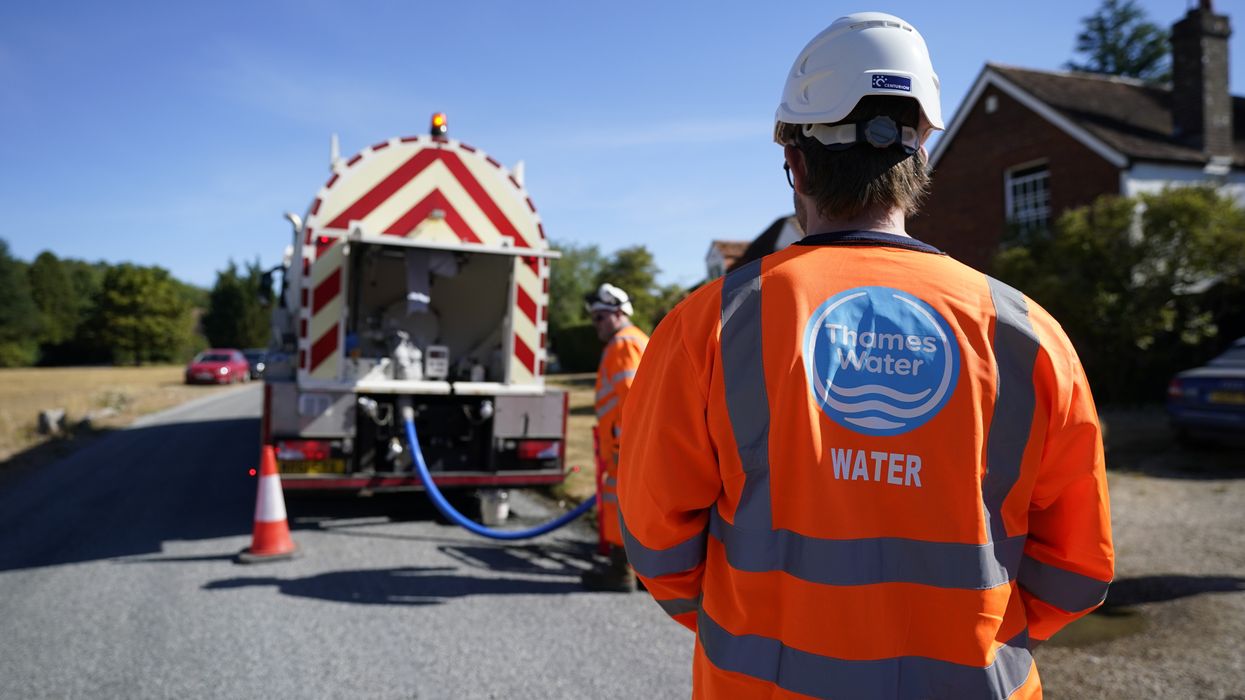 A worker from Thames Water delivering a temporary water supply from a tanker