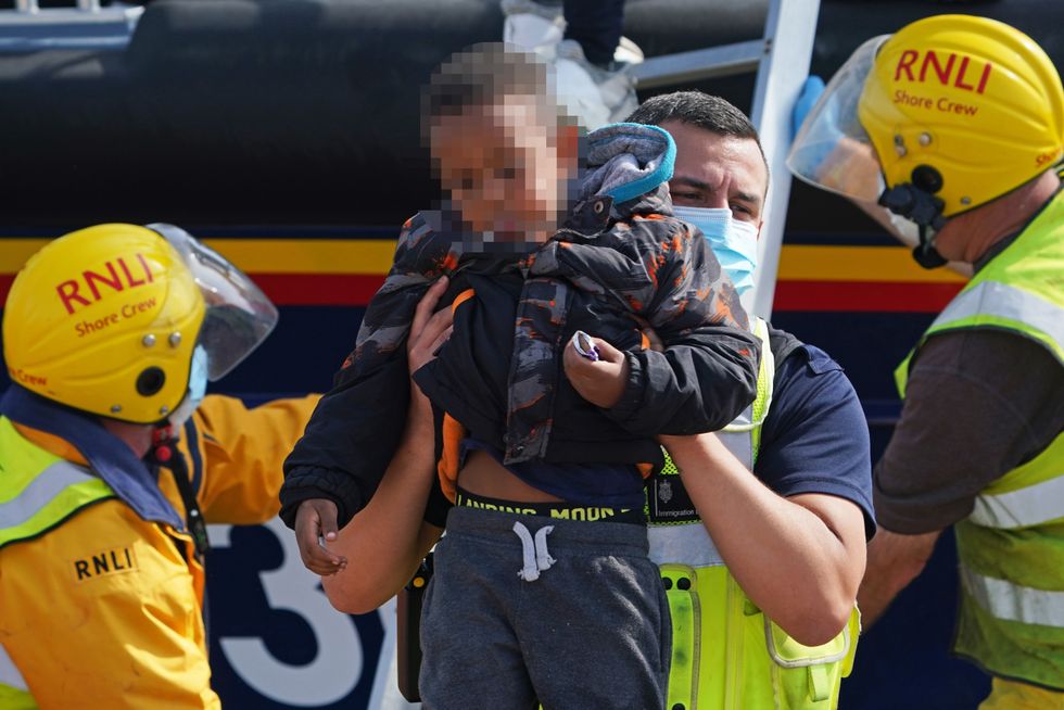 A young boy is brought ashore from the local lifeboat at Dungeness in Kent, along with a group of people thought to be migrants, after being picked-up following a small boat incident in the Channel.
