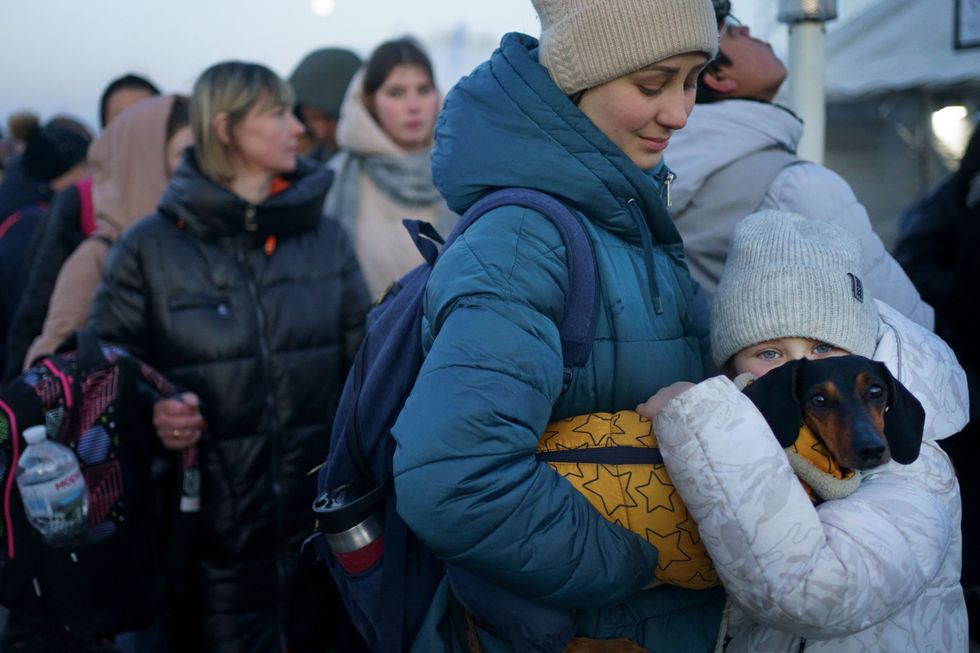 A young girl from Ukraine holds her dog as she waits with her mother for a bus to refuge accommodation after they crossed the border point from Ukraine into Medyka, Poland.