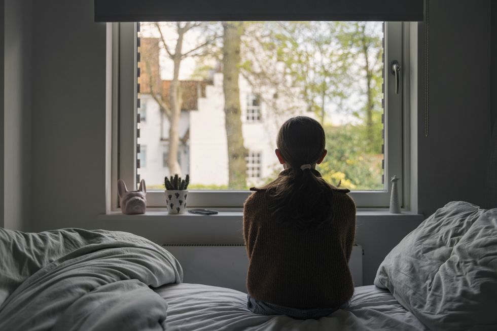 A young girl looks out of her bedroom window
