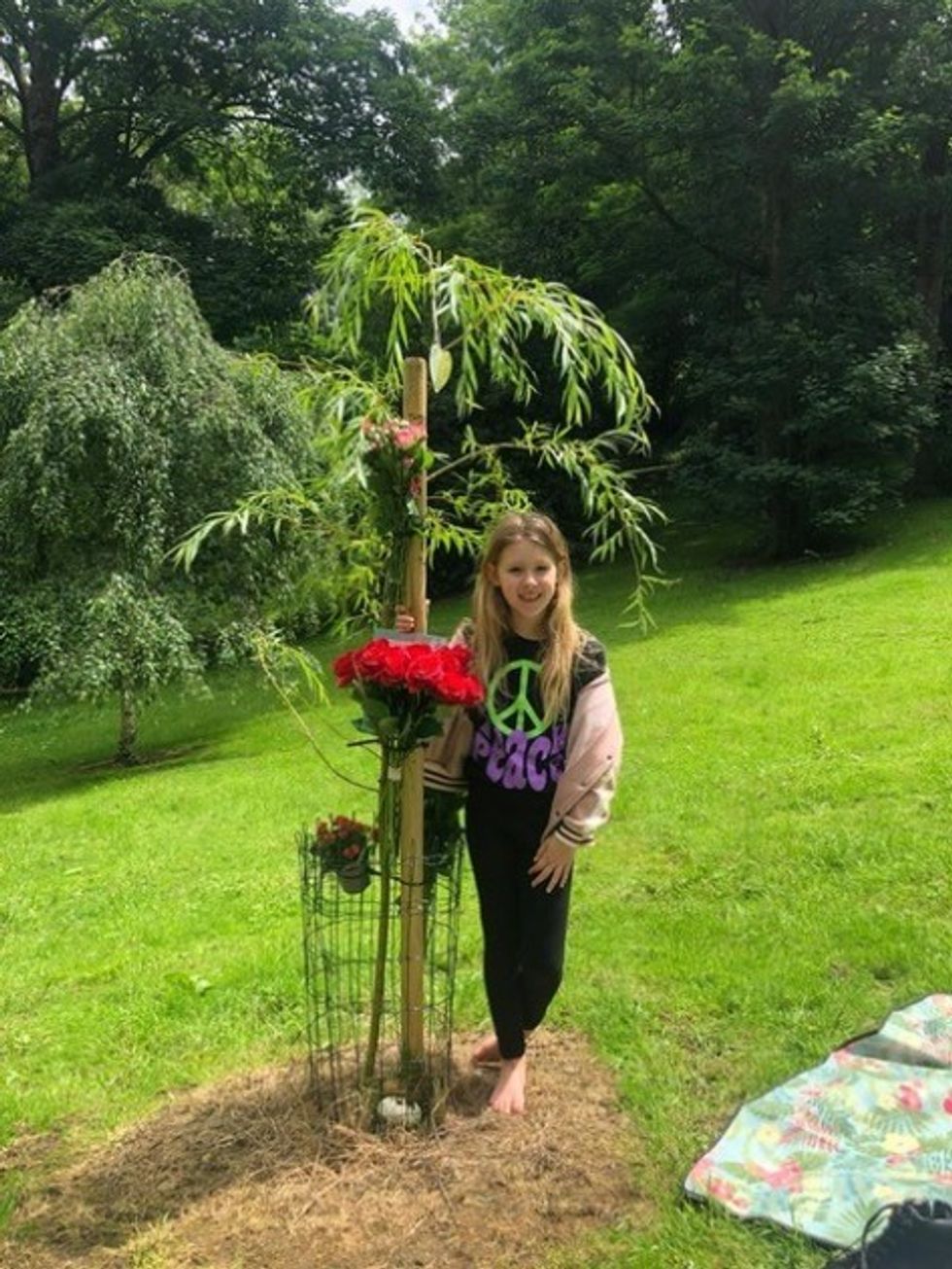 A young girl next to a tree