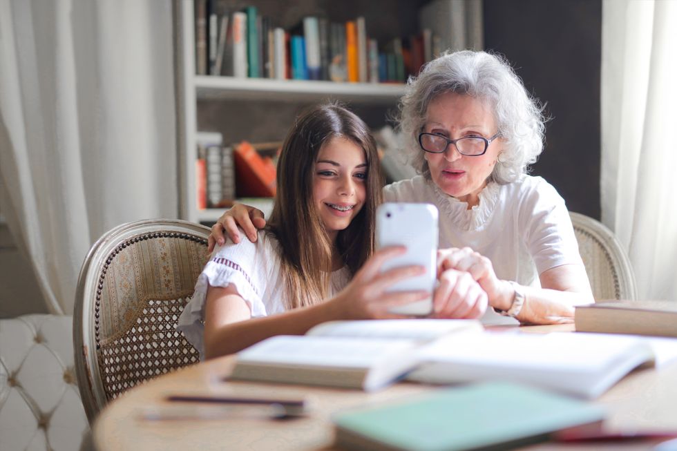 A young girl on her phone with an elderly woman