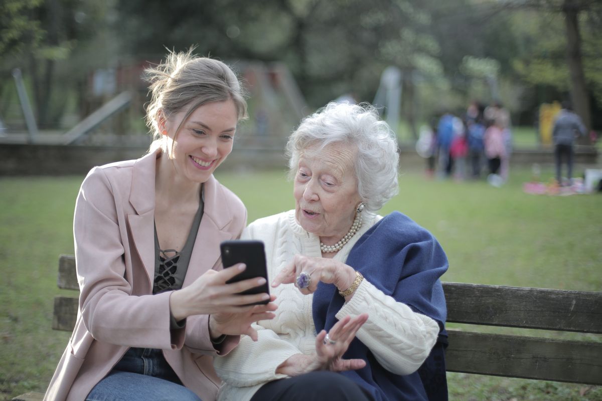 A young woman helps an elderly woman on a mobile