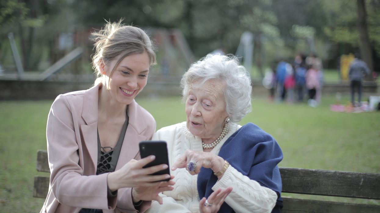 A young woman helps an elderly woman on a mobile