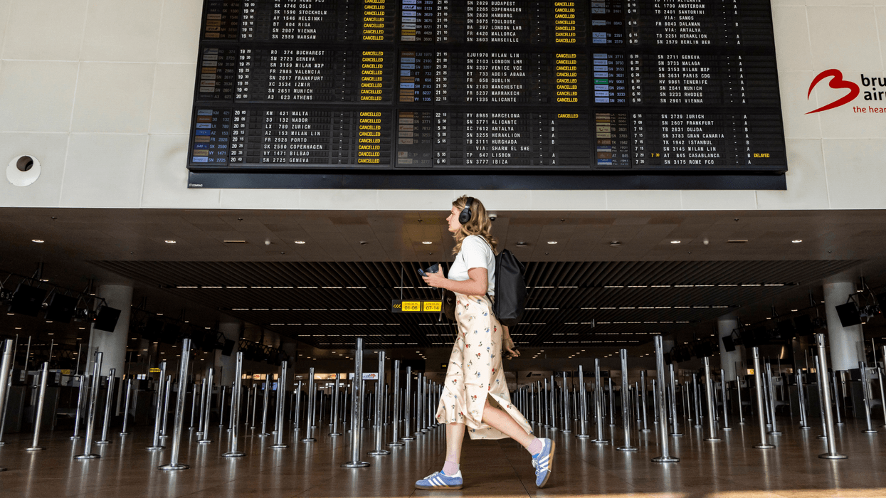 A young woman walking under the departure board