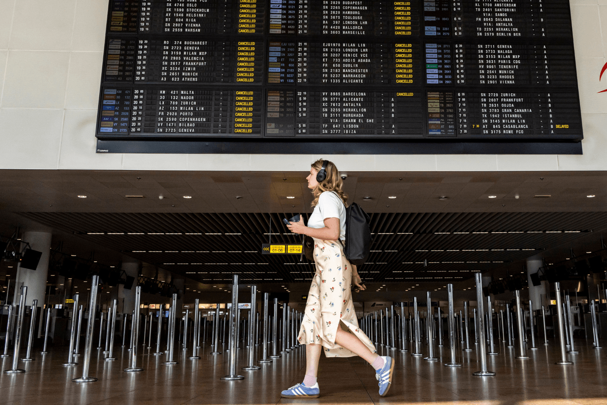 A young woman walking under the departure board