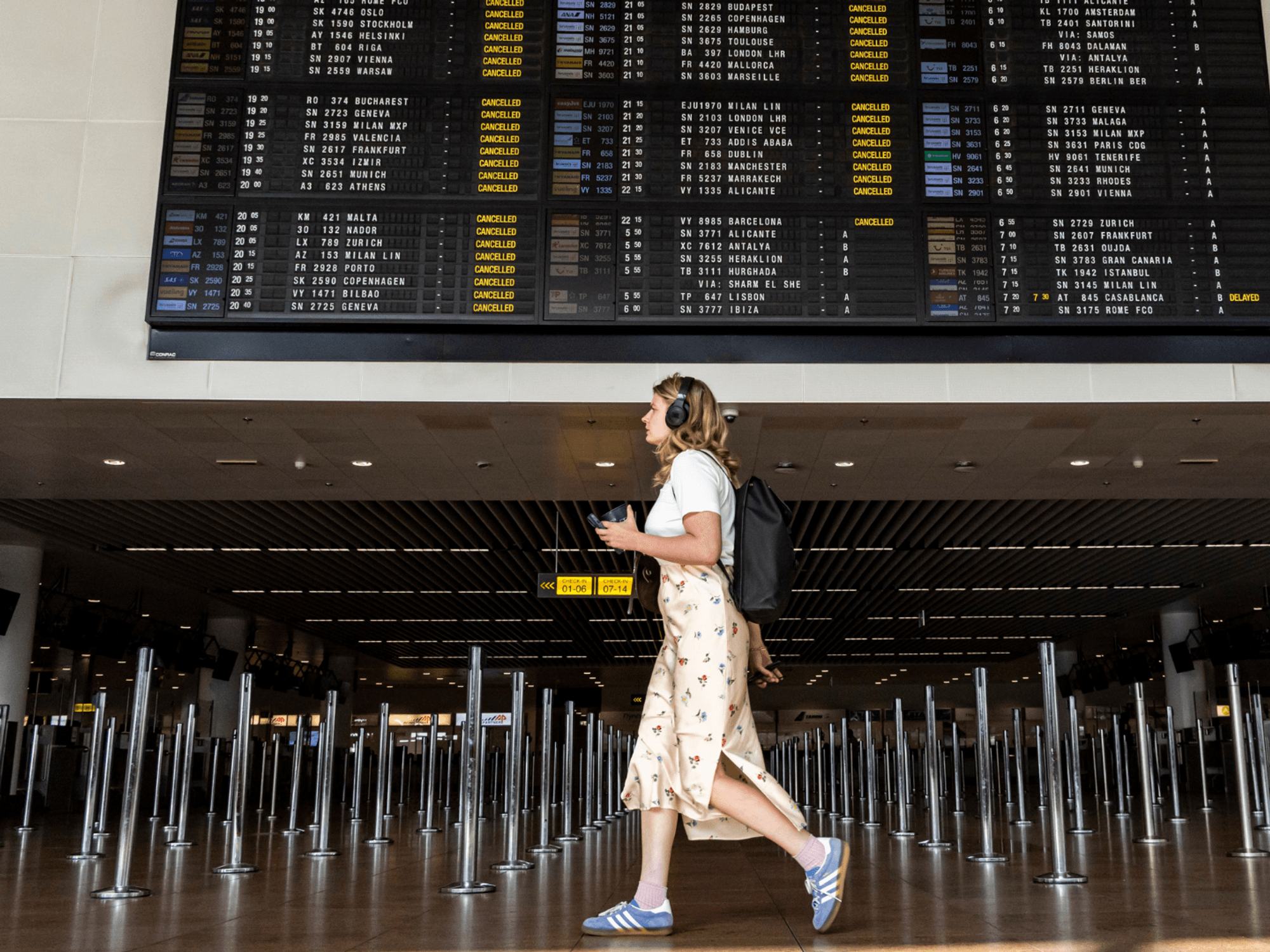 A young woman walking under the departure board