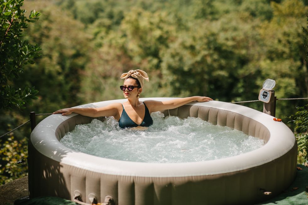 A young woman with a head tie enjoying a view of a Tuscany in September from a hot tub
