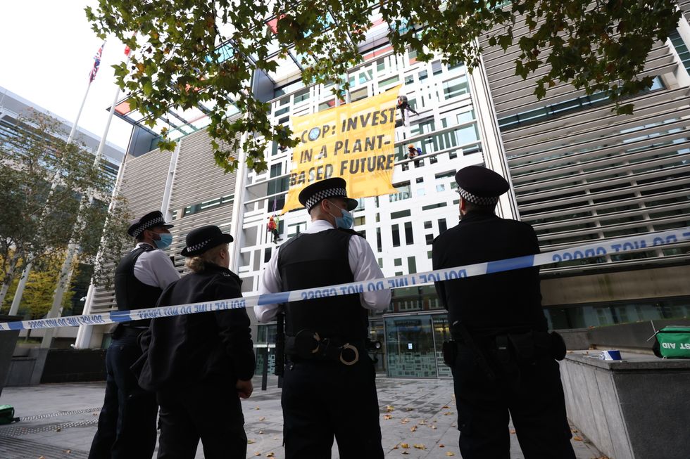 Activists from Animal Rebellion display a banner after scaling the outside of the Department for Environment, Food and Rural Affairs (Defra) in Westminster
