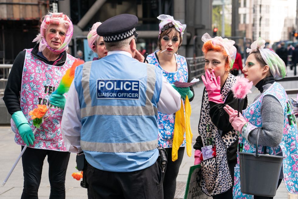 Activists from Extinction Rebellion dressed as cleaners speak to a police liaison officer outside Lloyds of London, in the City of London, as they call for Lloyds to stop insuring fossil fuel projects worldwide. Picture date: Tuesday April 12, 2022.