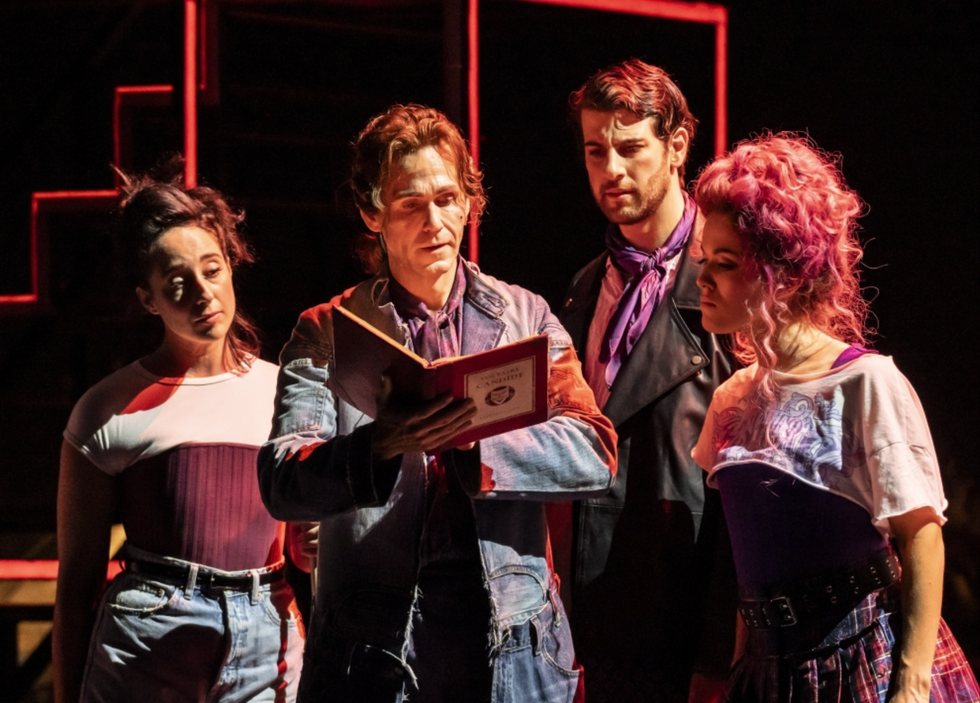 Actors gaze into a book on stage