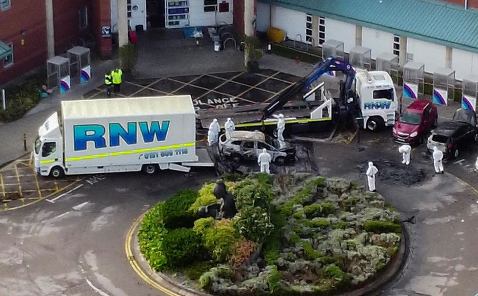 Aerial view of damaged car being removed by forensic officer after the explosion at the Liverpool Women's Hospital that killed one person and injured another