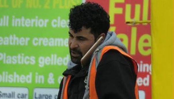 Ahmed using a telephone at his car wash in Burnley