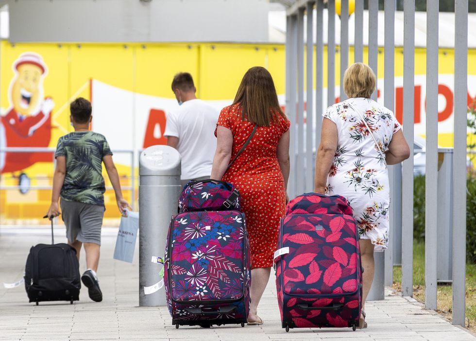 Air passengers with luggage walking towards the car park after leaving George Best Belfast City Airport.