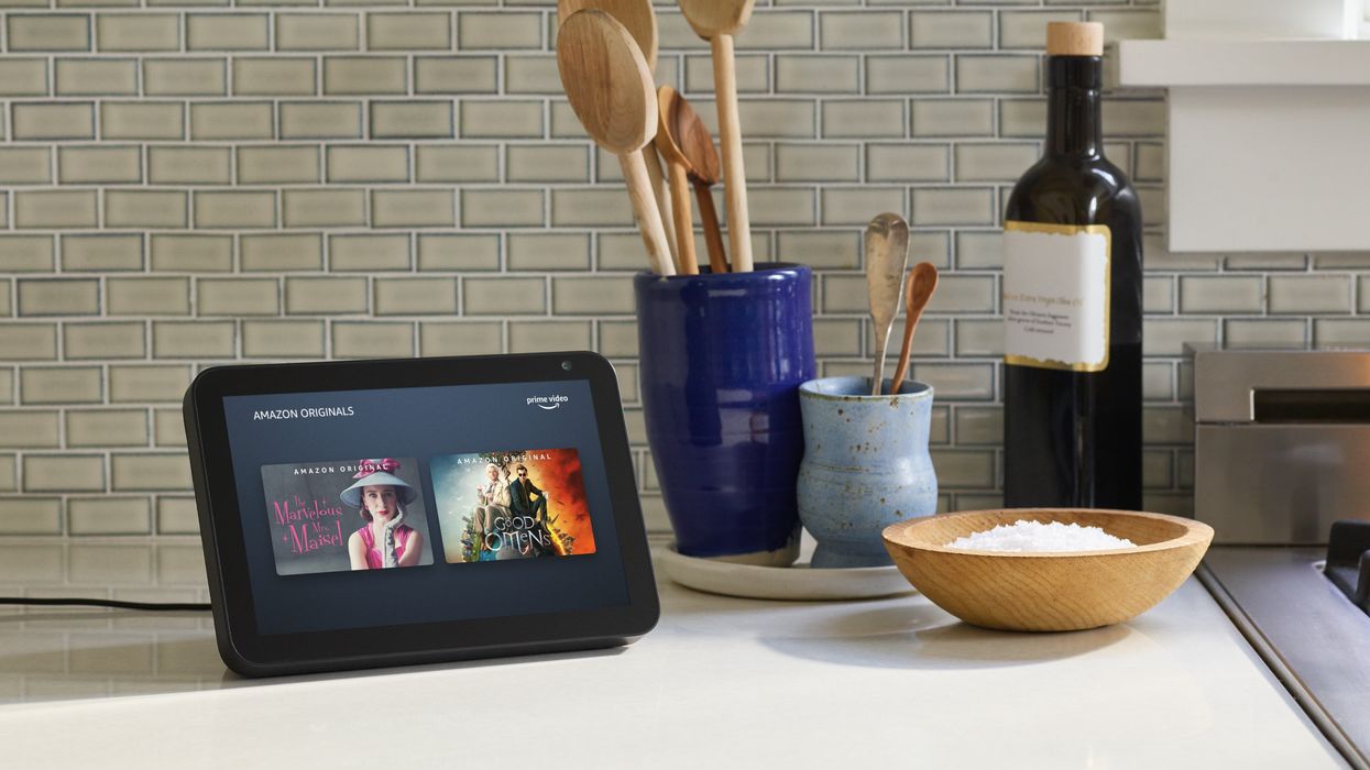 amazon echo show 5 pictured on a kitchen worktop with cooking utensils around it