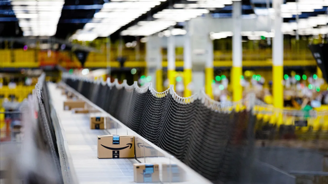 amazon parcels with the prime logo on the box shown on a conveyor belt inside a fulfilment centre
