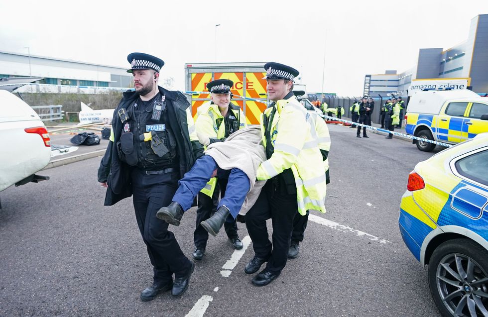 An activist from Extinction Rebellion is carried away by police after they blocked the entrance to the Amazon fulfilment centre in Tilbury, Essex, preventing lorries from entering or leaving on Black Friday, the global retail giant's busiest day of the year. Picture date: Friday November 26, 2021.