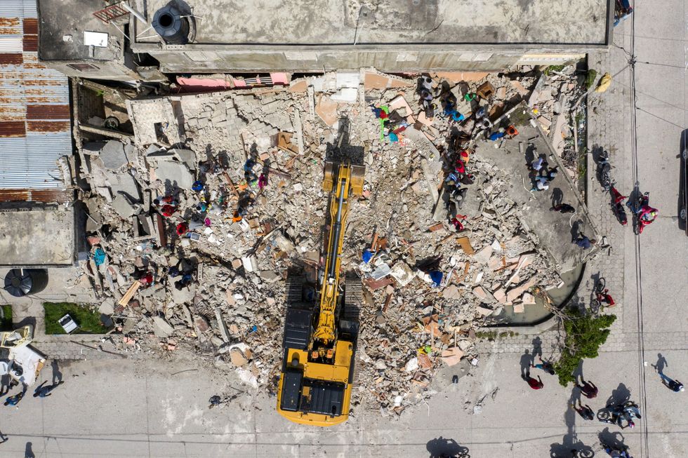 An aerial view of an excavator removing rubble from a destroyed building after Saturday's 7.2 magnitude quake, in Les Cayes, Haiti August 18, 2021. REUTERS/Ricardo Arduengo